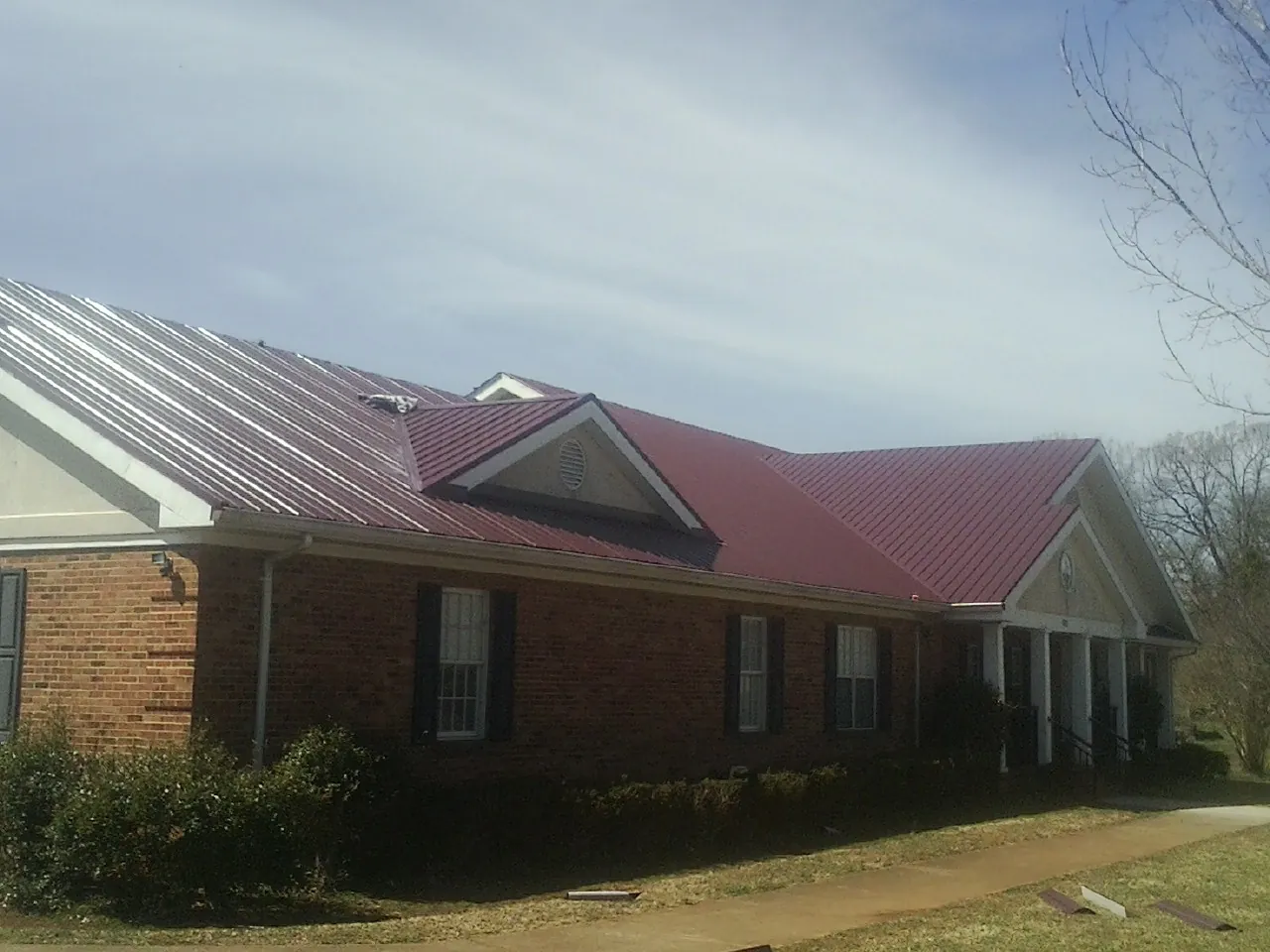 Red metal roof with gabled entries on a long brick building in Independence