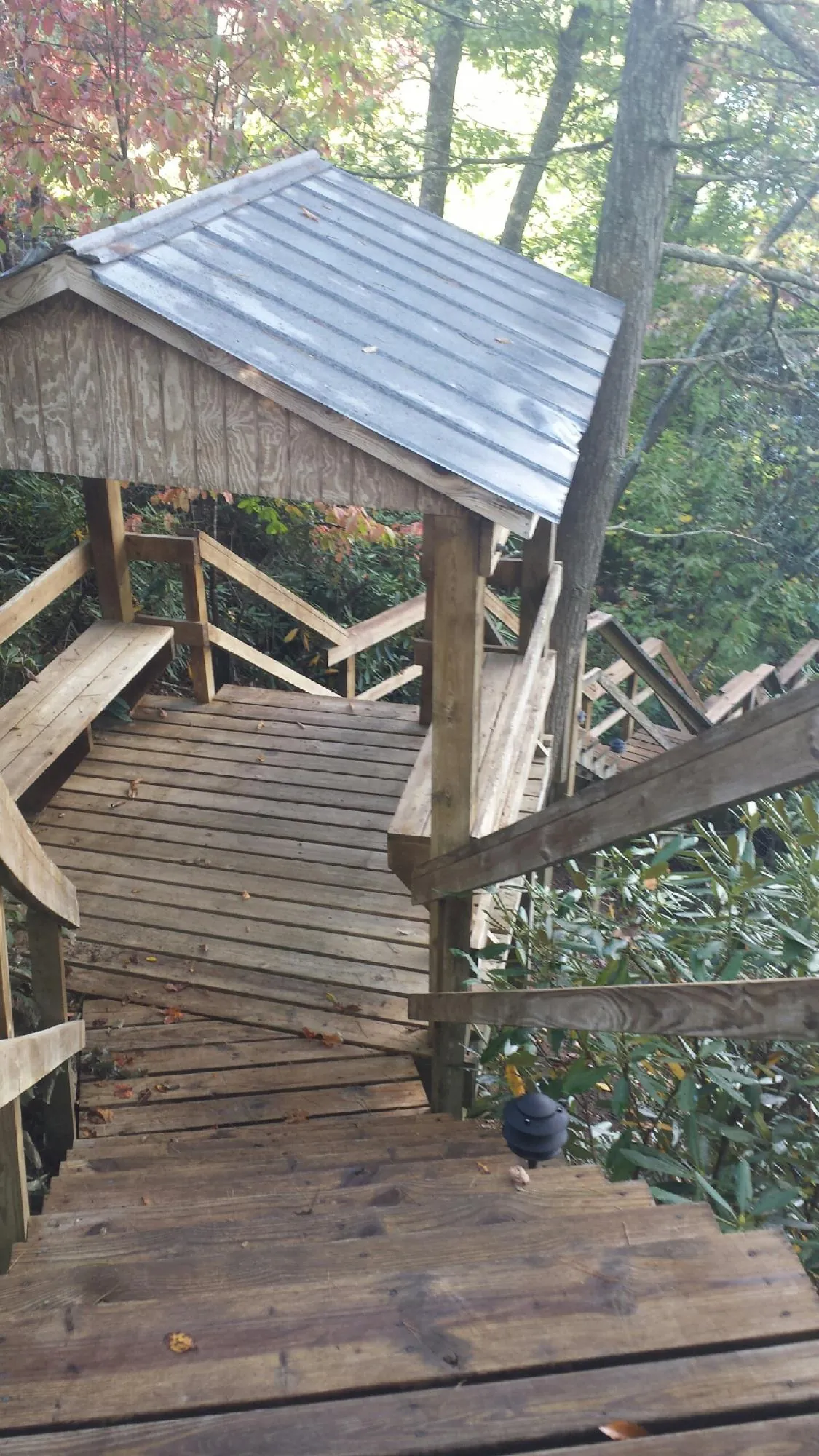 Metal roofed shelter over wooden steps on a wooded walkway — Skylight Repair & Installation work by our crew in Independence